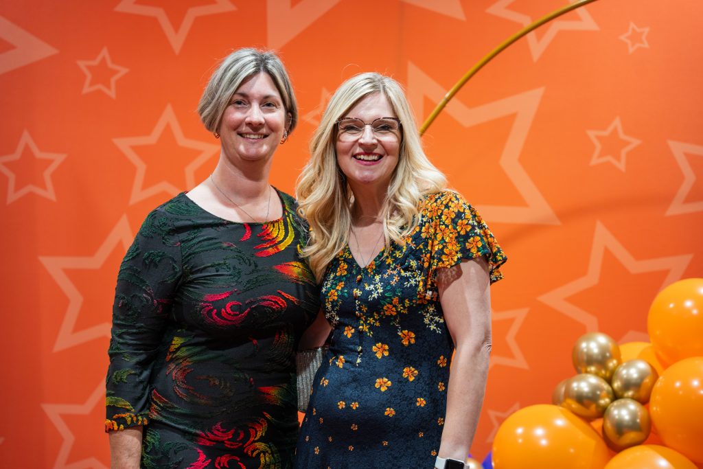 Two women at the film premier smiling to camera.