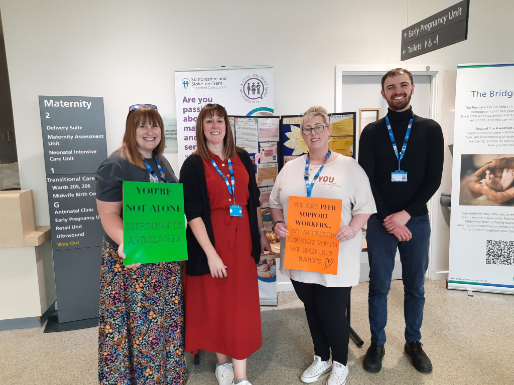 A group of Combined Healthcare staff standing in front of a stand at the Royal Stoke Hospital.