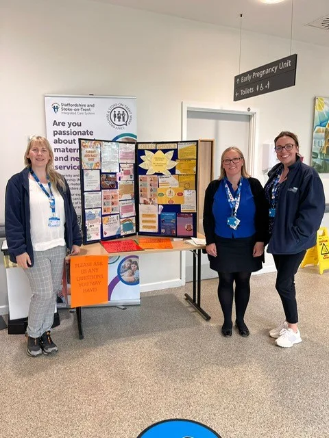 A group of staff standing in front of a stand at the Royal Stoke Hospital.
