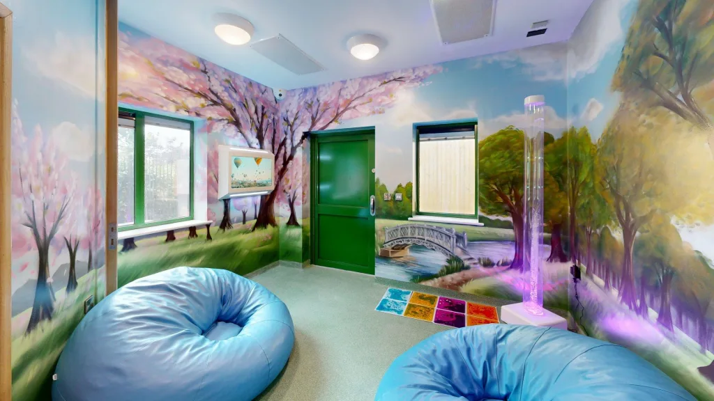 A photograph of the Peace Pod at the Darwin Centre, a room with a colourful nature mural, bean bags and sensory activities.